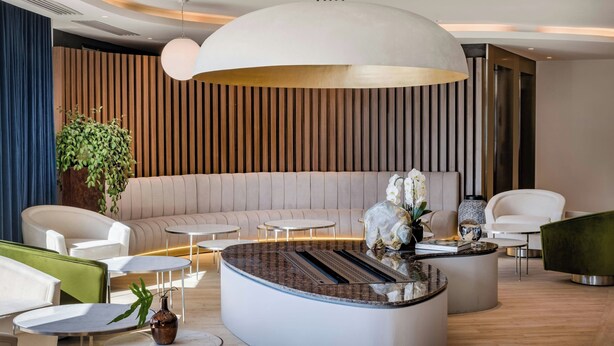 A modern lobby with a central seating area, a large light fixture, and a decorative plant. - AC Hotel Saint-Julien-en-Genevois (Saint-Julien-en-Genevois)