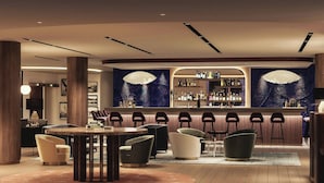 A modern bar area with a curved counter, multiple seating options, and a large screen. - AC Hotel Saint-Julien-en-Genevois (Saint-Julien-en-Genevois)