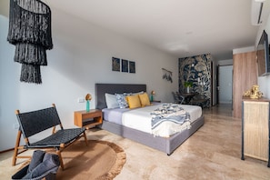 Un dormitorio con cama, una silla, una mesita de noche, un adorno en la pared y una planta decorativa.