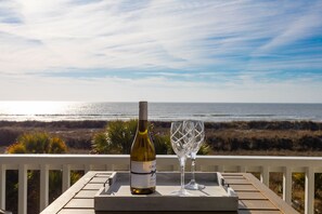Een fles wijn en een glas op een houten tafel, met uitzicht op de oceaan.