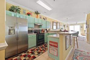Une cuisine moderne avec des armoires de couleur turquoise, des appareils en acier inoxydable et un îlot central.