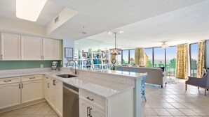 A modern kitchen with white cabinetry, a large island, and a dining area with a view.
