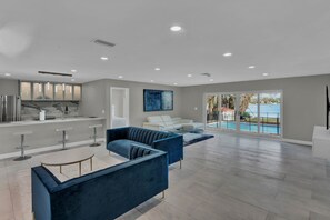 Un salón amplio con cocina, un sofá blanco y un sofá azul.