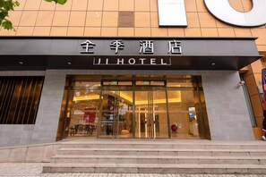 A hotel entrance with a modern design, featuring a large glass facade and a prominent sign above the doors. - Ji Hotel (Shanghai)