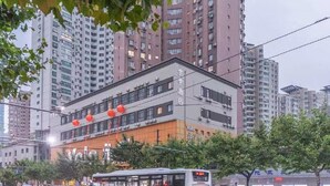 Ett hotell med flera våningar, en modern fasad, luftkonditioneringsanläggningar och en väl synlig skylt med texten ”Yolo Hotel”.