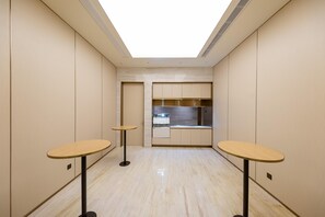 A corridor with two round tables, a kitchenette, and a skylight. - Ji Hotel (Shanghai)