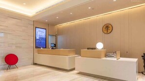 Ett välkomnande område med modern design, med en receptionsdisk, en digital skärm och en röd stol.