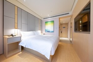 A modern hotel room with a large bed, bedside table, and a painting on the wall. - Ji Hotel (Shanghai)