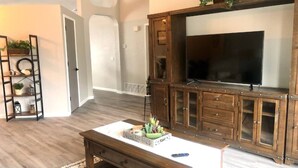 Un salon avec un meuble de rangement en bois pour l’équipement audiovisuel, une table basse et un téléviseur.