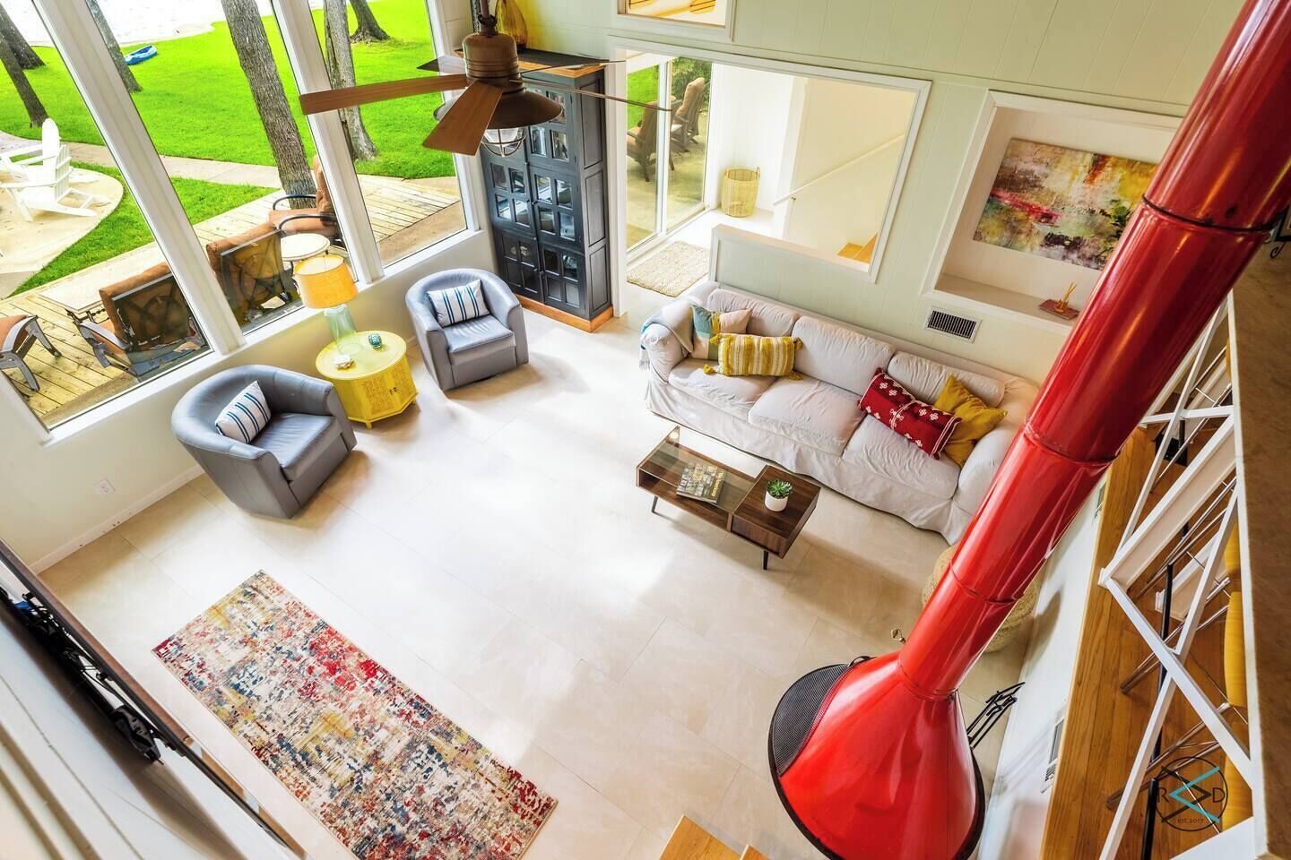 Un amplio salón con un gran ventanal, una escalera espiral roja y un diseño de interiores moderno.