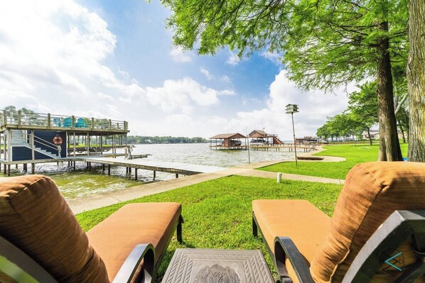 A lakeside view with a dock, lounge chairs, and a gazebo.