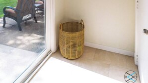 Una habitación con un ventanal grande, una cesta de mimbre, un banco y un letrero que dice 'Be Still'.