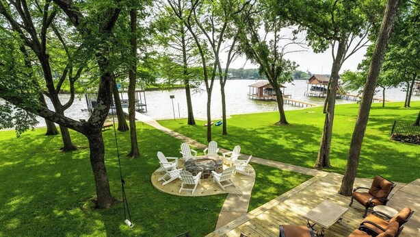 Un patio con fogón, mobiliario exterior y vista a un lago.