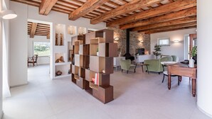 Een ruime woonkamer met zichtbare houten balken, een moderne boekenkast en een stenen muur.