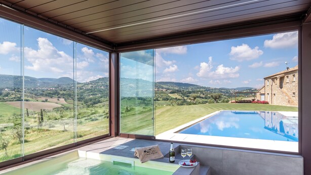 Een moderne spa met een zwembad en een prachtig uitzicht op een groen landschap en een stenen gebouw.