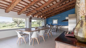 Een moderne keuken met een groot kookeiland, witte stoelen en uitzicht op het landschap.