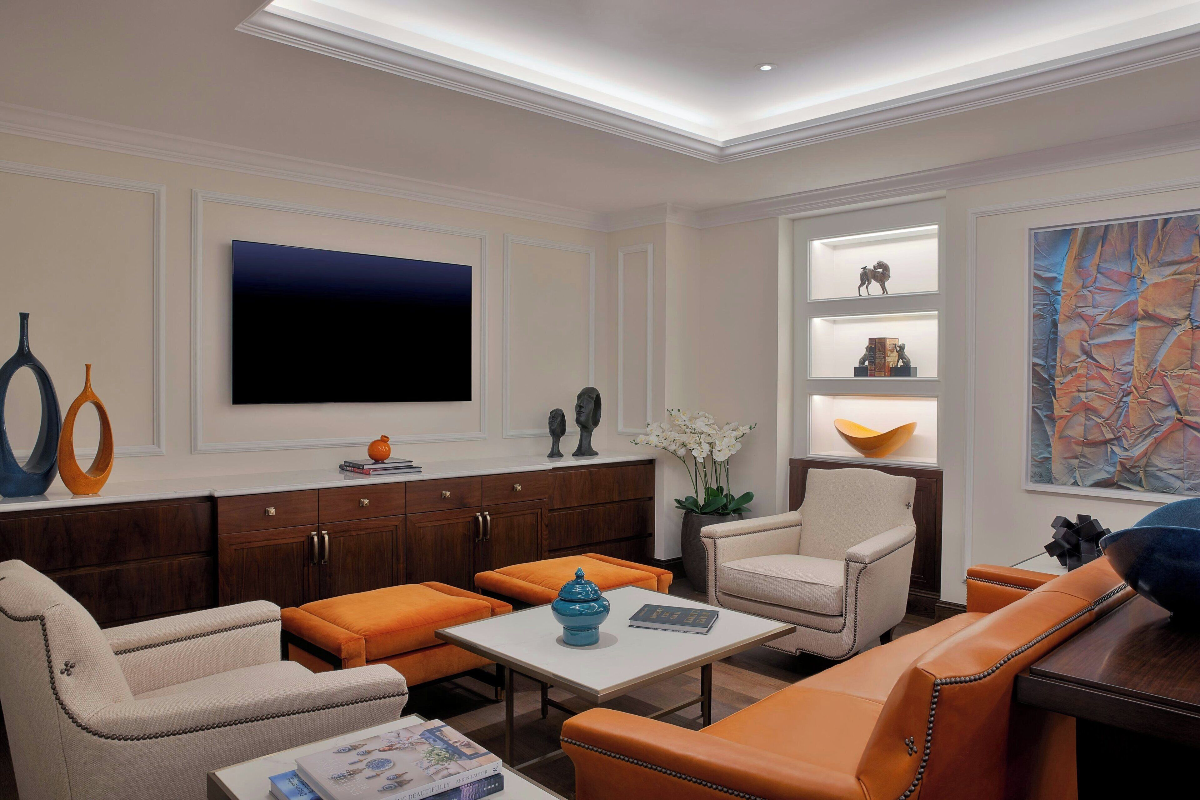 A modern living room with a flat-screen TV, leather sofas, a coffee table, and decorative items on shelves.