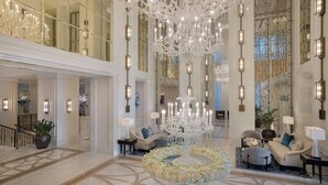 Un vestíbulo amplio con una gran araña, muebles elegantes y un arreglo floral decorativo.