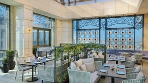Un amplio comedor interior con techos altos, ventanas grandes y vistas a la ciudad.