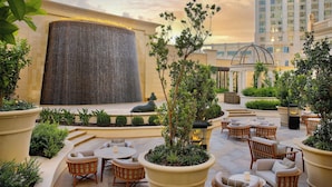 Un patio al aire libre con arreglos de asientos, un muro decorativo y una fuente.