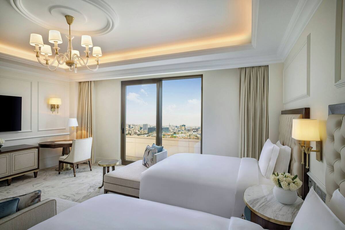 Une chambre d’hôtel avec deux lits, un bureau, une télévision et une vue sur la ville.