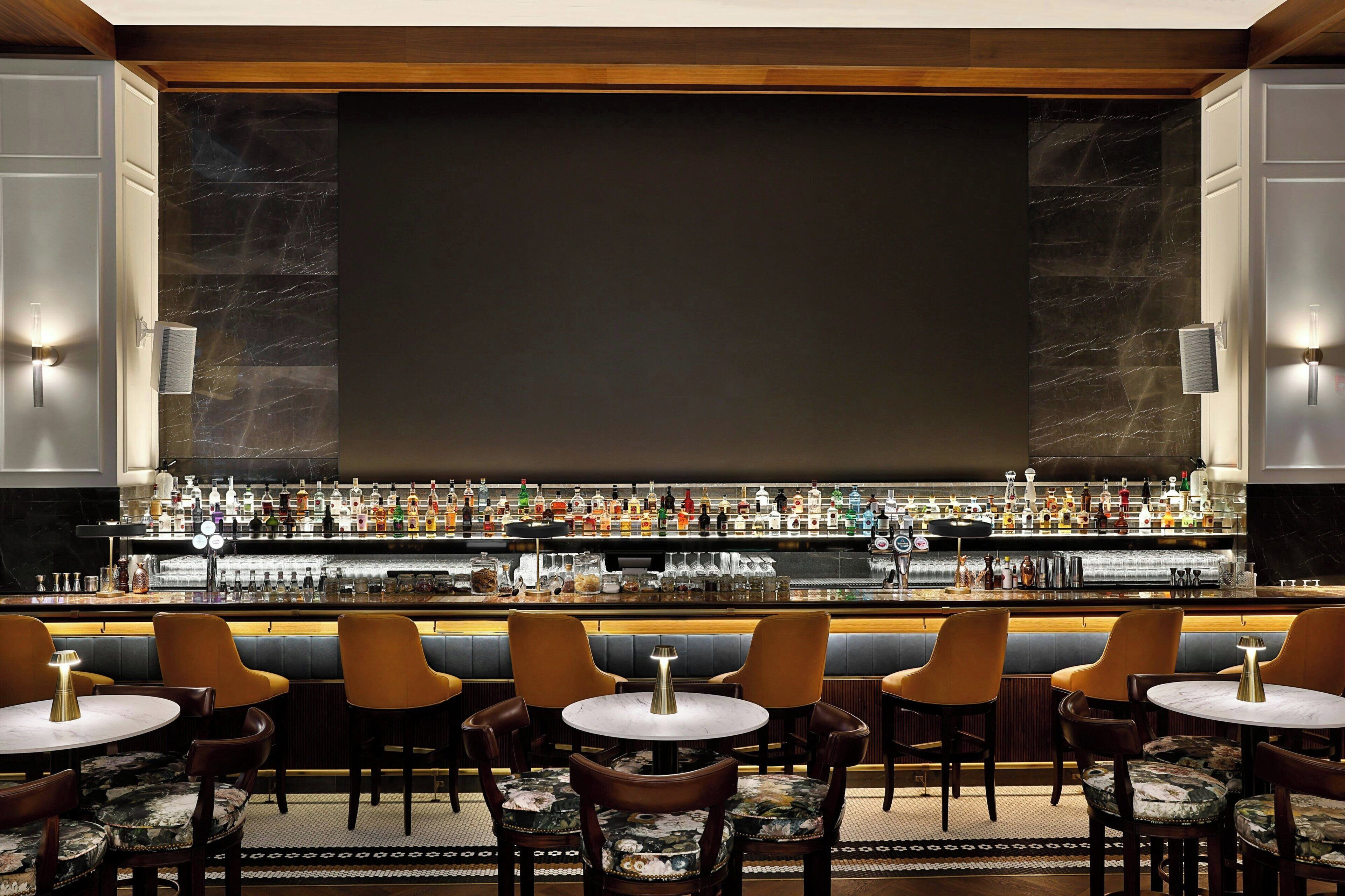 A bar area with a marble wall, multiple seating options, and a well-stocked bar counter.