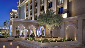 Un patio de hotel con un árbol central, zonas de estar y una piscina.