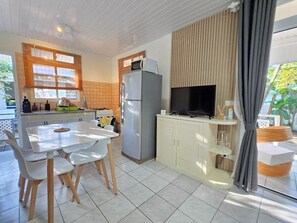 Una cocina compacta con comedor, refrigerador, microondas y televisor.