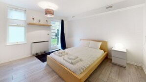 Une chambre moderne avec un lit en bois, une table de chevet avec une lampe, un radiateur et une fenêtre avec des rideaux.