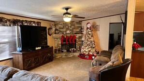 A living room with a fireplace, a Christmas tree, and a television. - Nice and Cozy cabin, 3 bedroom and 2 bathroom. (Ruidoso)