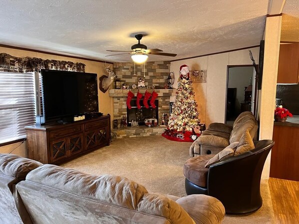Ein Wohnzimmer mit Kamin, Weihnachtsbaum und Fernseher.