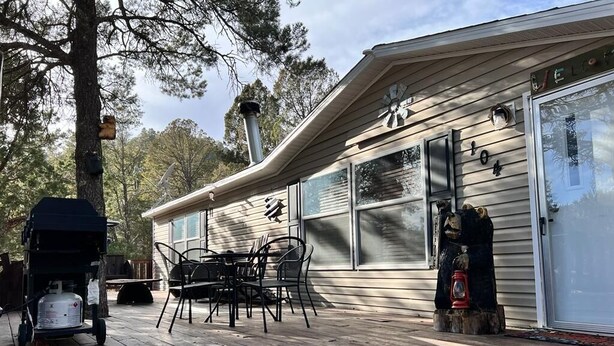 A wooden deck with outdoor furniture, a barbecue grill, and a propane tank. - Nice and Cozy cabin, 3 bedroom and 2 bathroom. (Ruidoso)