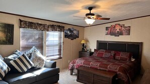 A bedroom with a bed, a nightstand, a lamp, a ceiling fan, and a window with blinds. - Nice and Cozy cabin, 3 bedroom and 2 bathroom. (Ruidoso)