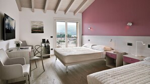 Une chambre moderne avec un grand lit, un bureau et une chaise. Elle dispose d’un balcon avec vue sur la ville.