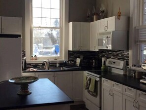 A modern kitchen with white cabinets, a black countertop, a microwave, and a dishwasher.