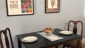 Una mesa de comedor con dos sillas, un cuenco de fruta y dos platos.
