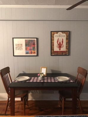 Une table à manger avec deux chaises, une affiche encadrée représentant un écrevisse et une affiche encadrée représentant un festival consacré à l’écrevisse.