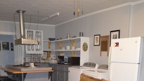 Una sala de estar acogedora con un sofá, un tapete estampado y una cocina con estufa, refrigerador y taburetes de bar.