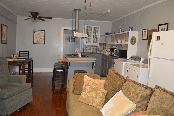A compact living space with a kitchenette, a dining area, and a seating area with a sofa and chairs.
