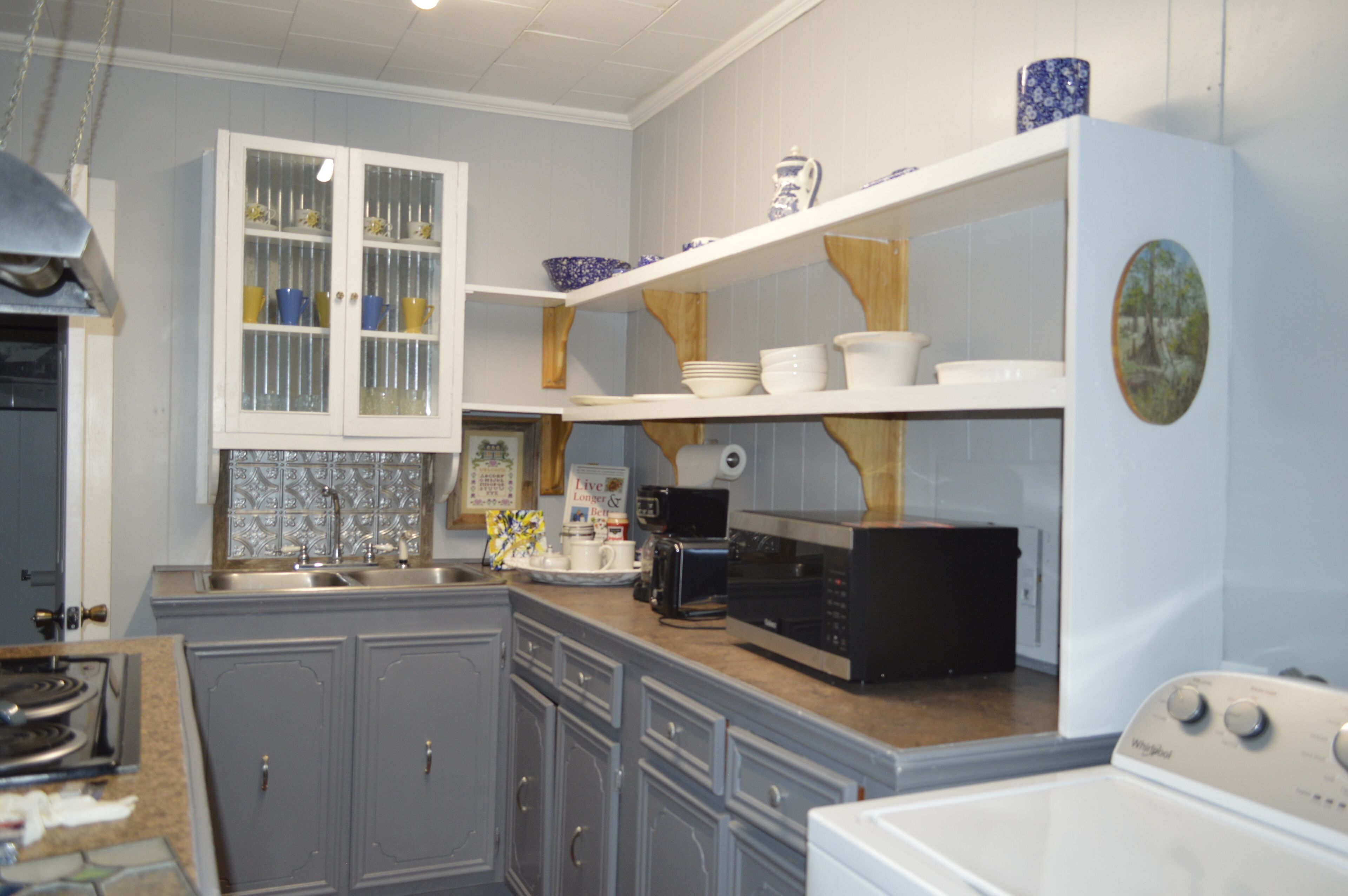 A kitchen with grey cabinets, a microwave, a toaster, and a dishwasher.