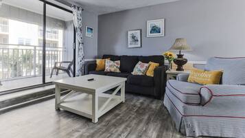 A living room with a sofa, a coffee table, and a lamp. There are two framed pictures on the wall.