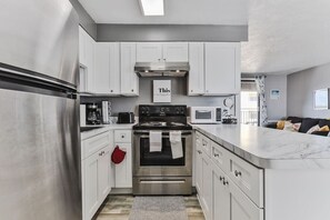 A modern kitchen with stainless steel appliances, white cabinetry, and a central island.