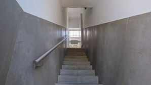 A staircase with metal railings and concrete walls, leading to a bright interior space. - GuestReady - Port Studio 3 (Vila Nova de Gaia)