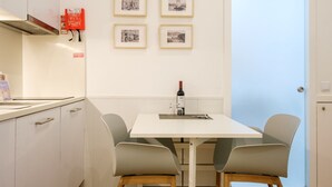 A small kitchenette with a white countertop, a wine bottle, and framed photographs on the wall. - GuestReady - Port Studio 4 (Vila Nova de Gaia)