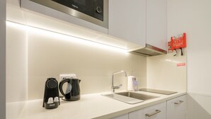 A modern kitchen with a stainless steel sink, a coffee maker, and a kettle on the counter. - GuestReady - Port Studio 4 (Vila Nova de Gaia)
