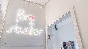A sign with illuminated letters spelling 'port studios' on a white wall.
