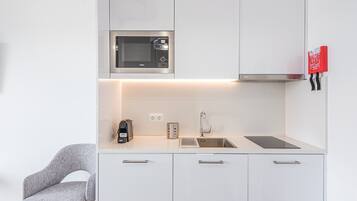 Una cocina moderna con microondas integrado, cafetera y lavamanos.