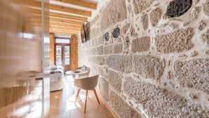 A room with a stone wall, wooden beams, a round table, and a sofa. - GuestReady - Miragaia Stone Studio 1F (Porto)