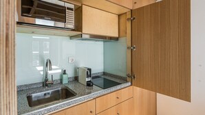 A compact kitchen with a microwave, sink, and a compact coffee maker. - GuestReady - Miragaia Stone Studio 1F (Porto)
