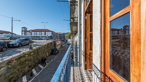 A narrow street with a stone wall and a wooden building with a balcony. - GuestReady - Miragaia Stone Studio 1F (Porto)